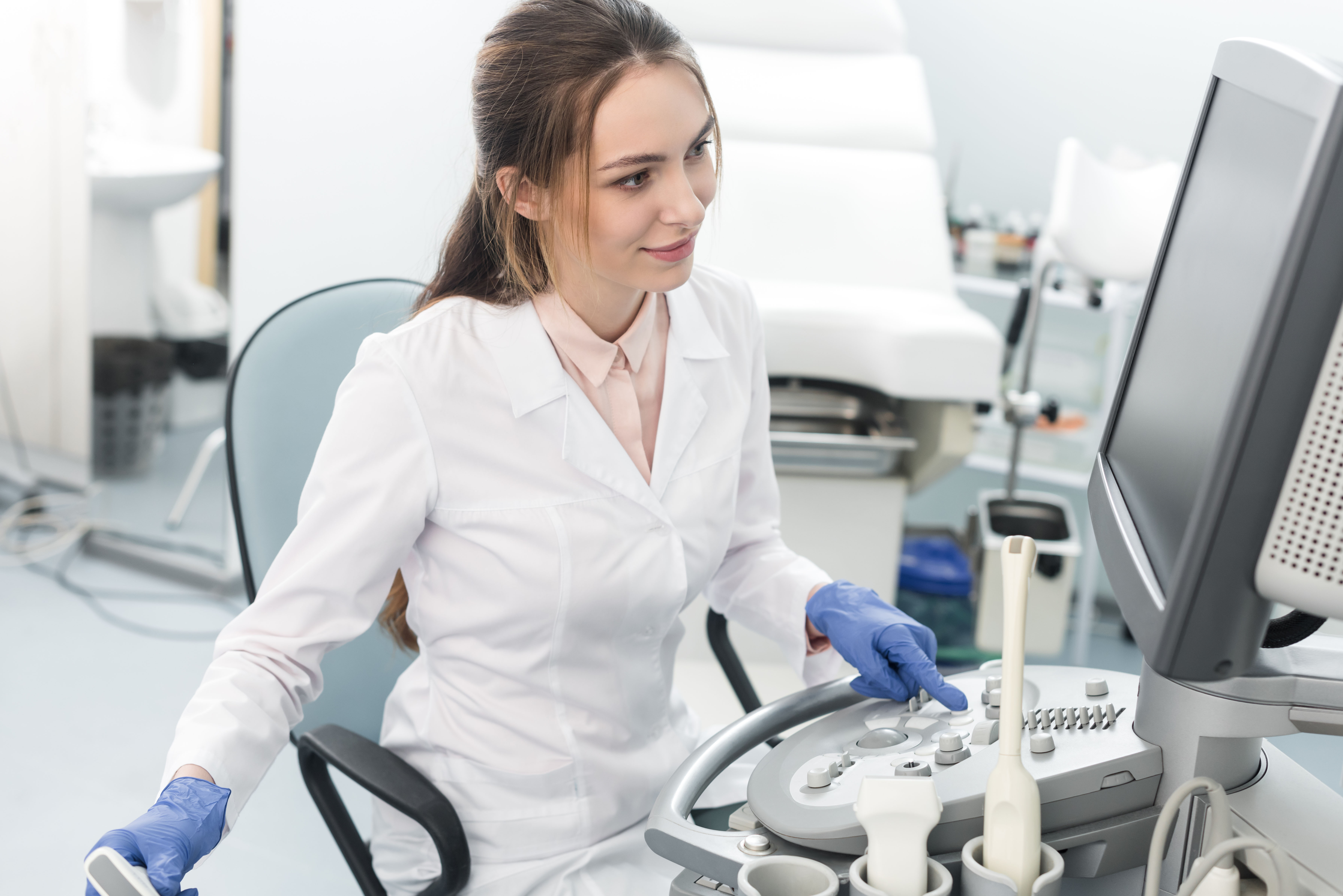 young smiling doctor working with ultrasound scanner in clinic