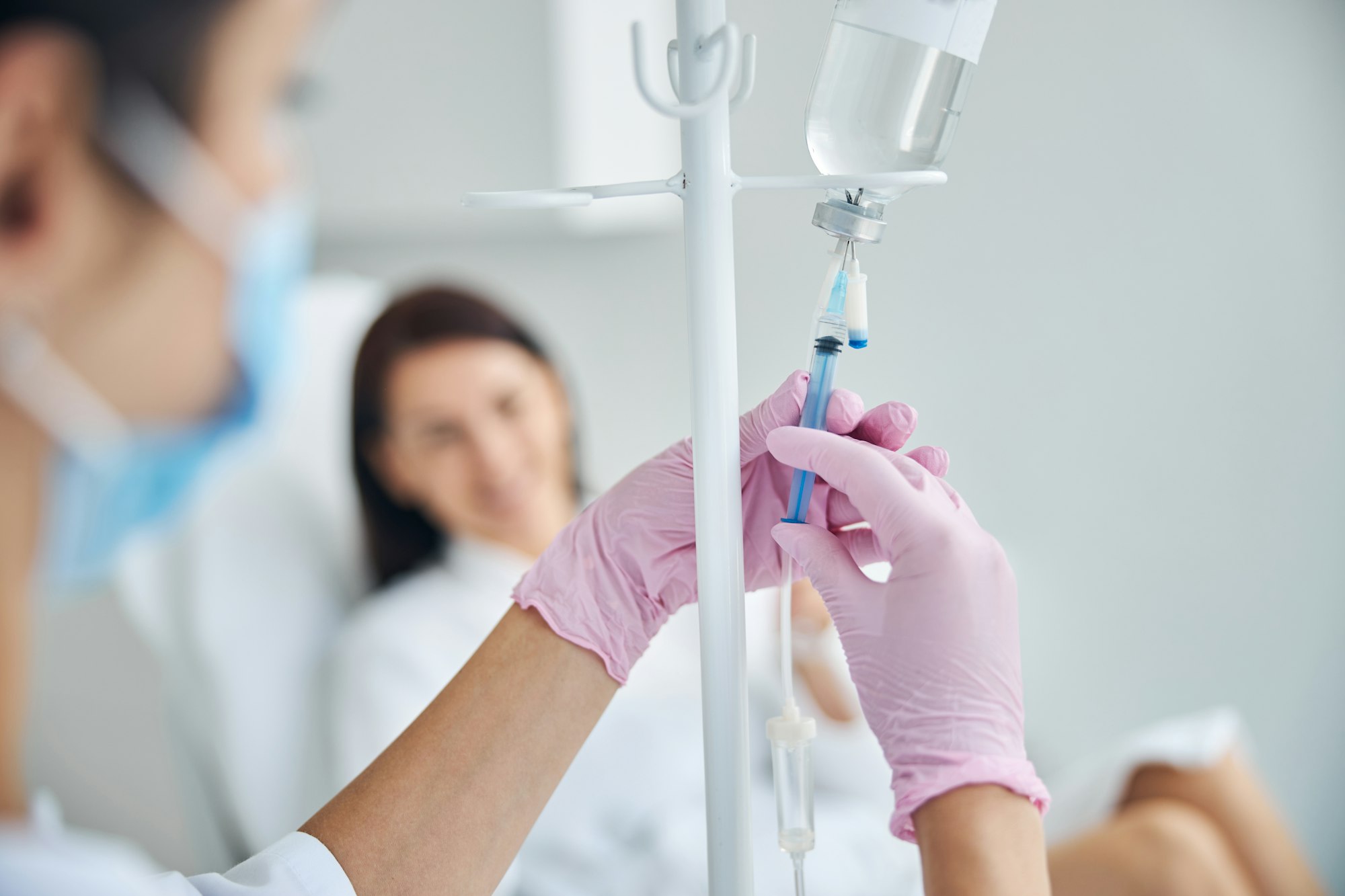 Qualified nurse adding a medication to an infusion bottle